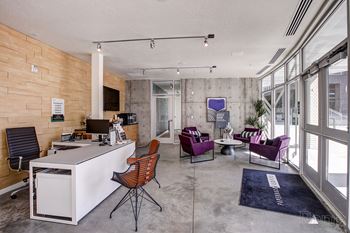 A modern office space with a white desk, purple chairs, and a wooden wall.